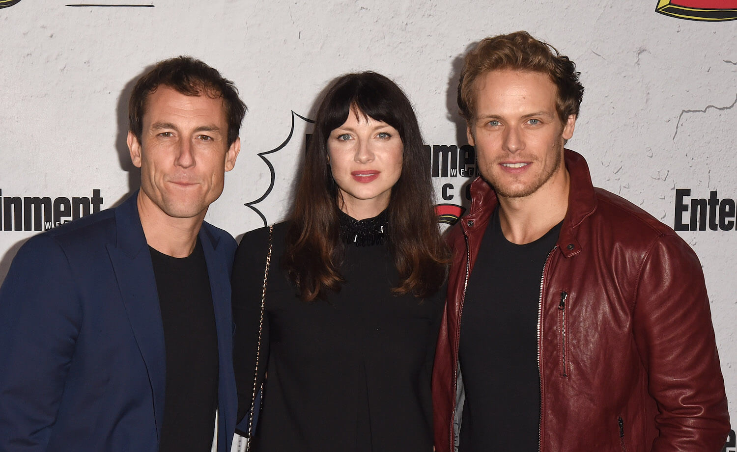 Tobias Menzies, Caitriona Balfe, and Sam Heughan of 'Outlander' standing side by side and smiling
