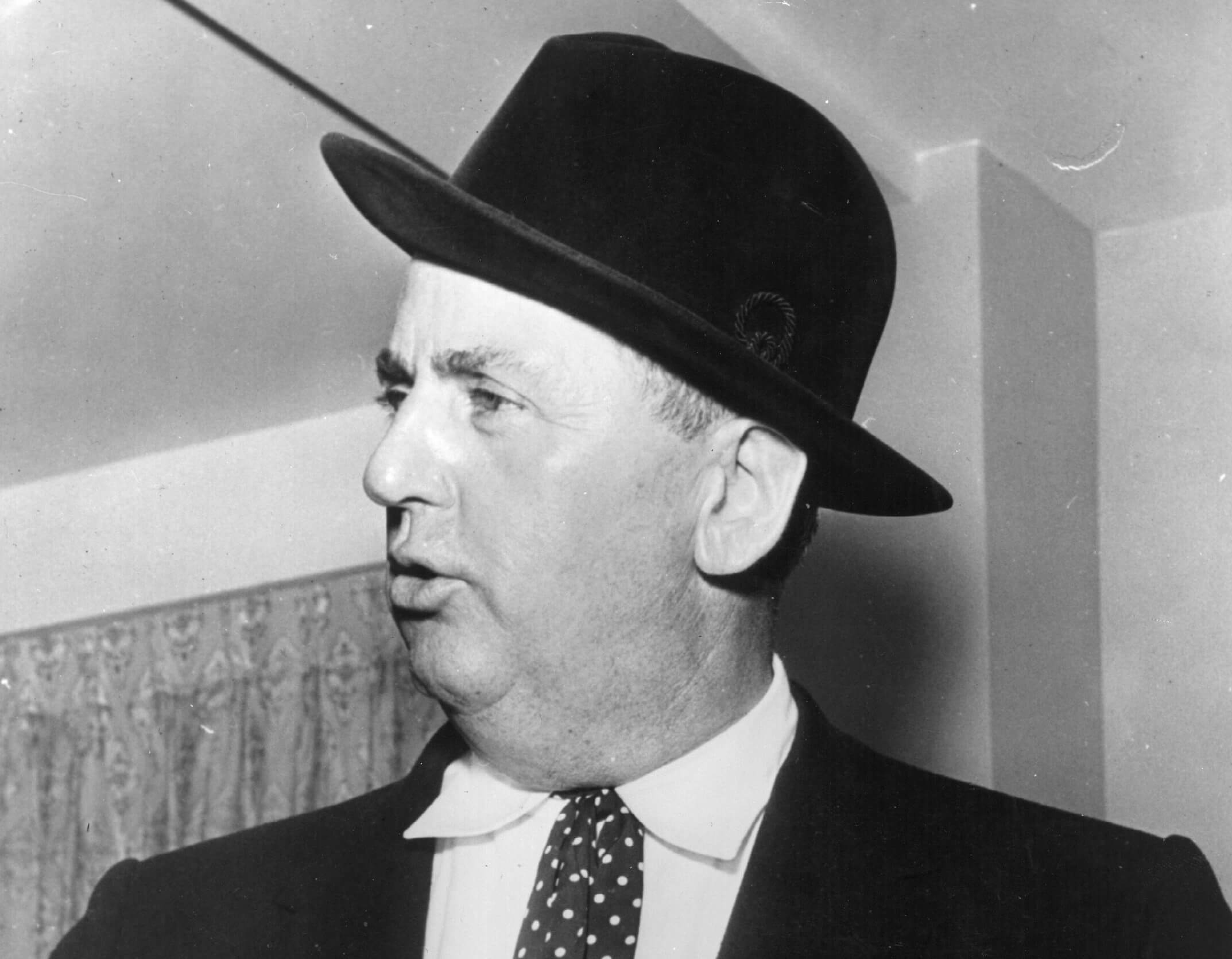 A black and white picture of Elvis' manager Tom Parker wearing a suit and bowler hat.