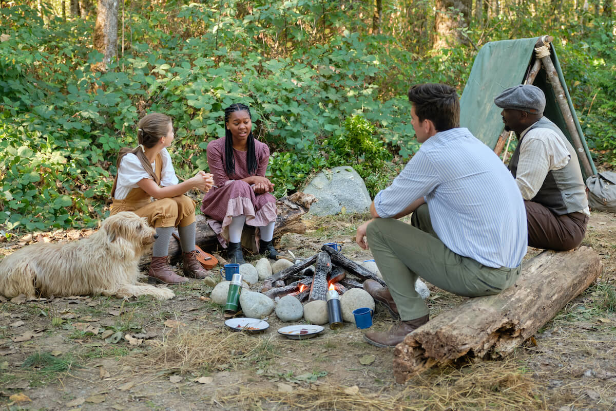 Allie, Angela, Josephe, and Nathan sitting around a campfire in 'When Calls the Heart' Season 10 Episode 5