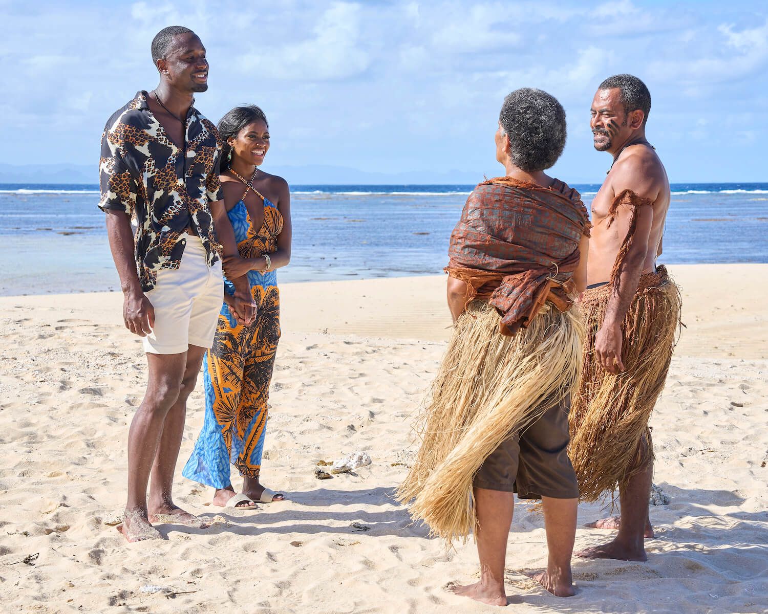 Xavier Bonner and Charity Lawson in 'The Bachelorette' 2023 standing on the beach in front of an older couple wearing island clothing