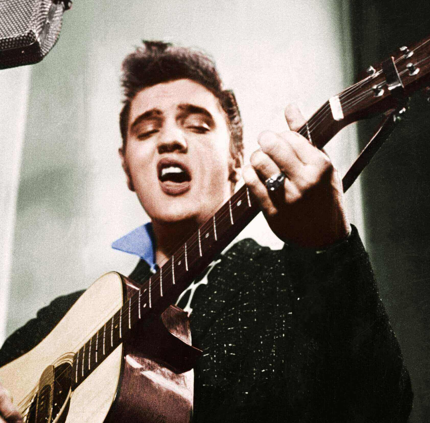 Elvis Presley singing and holding a guitar