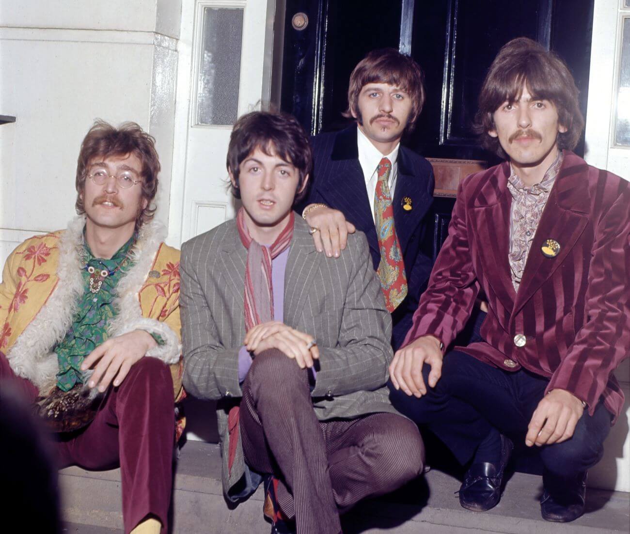The Beatles sit on a doorstep together.