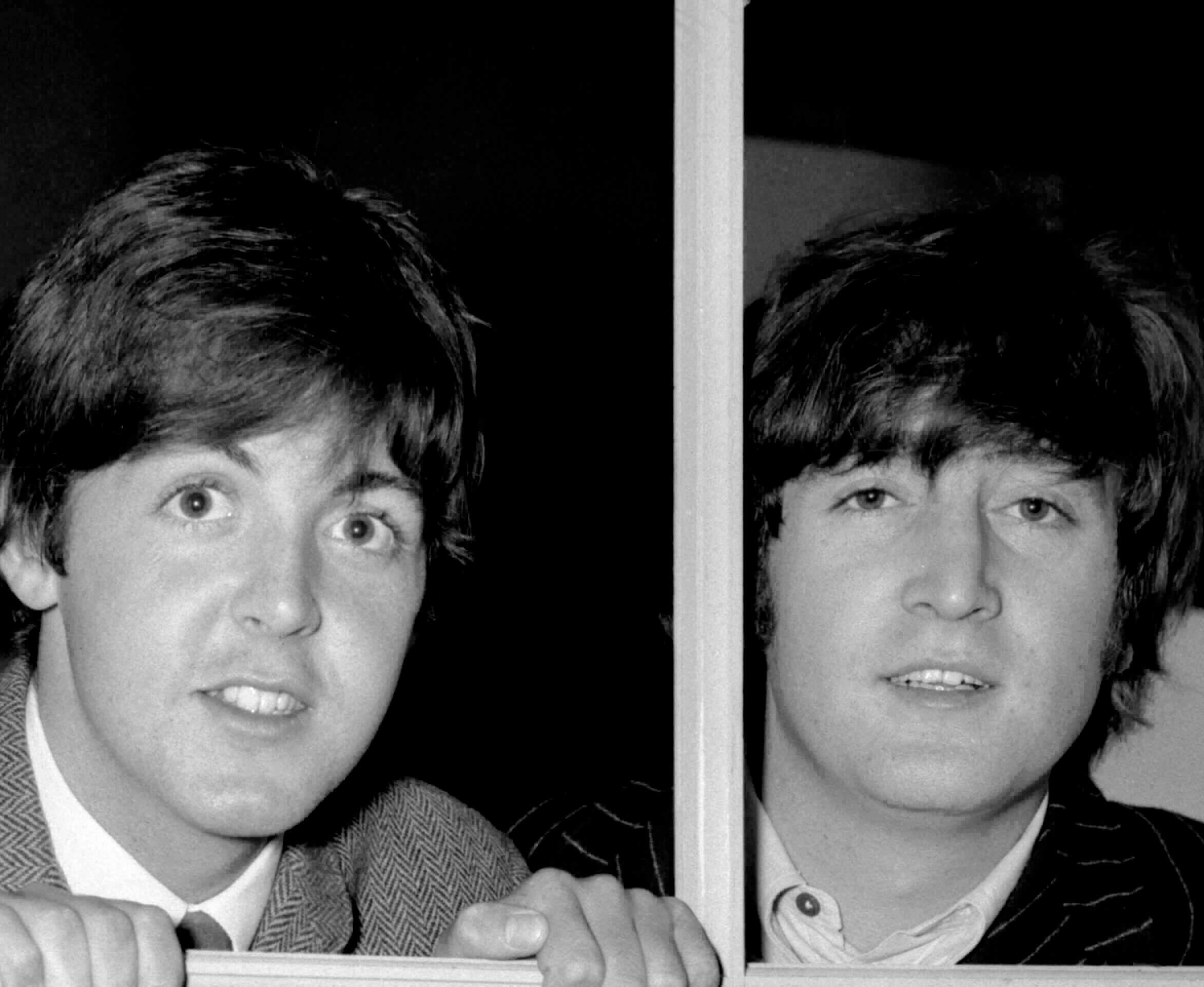 The Beatles' Paul McCartney and John Lennon looking through a window