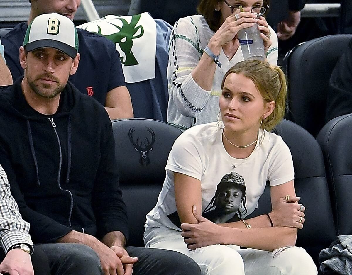 Aaron Rodgers and Mallory Edens, whose individual net worth doesn't stack up to the athlete's, look on before Bucks playoff game