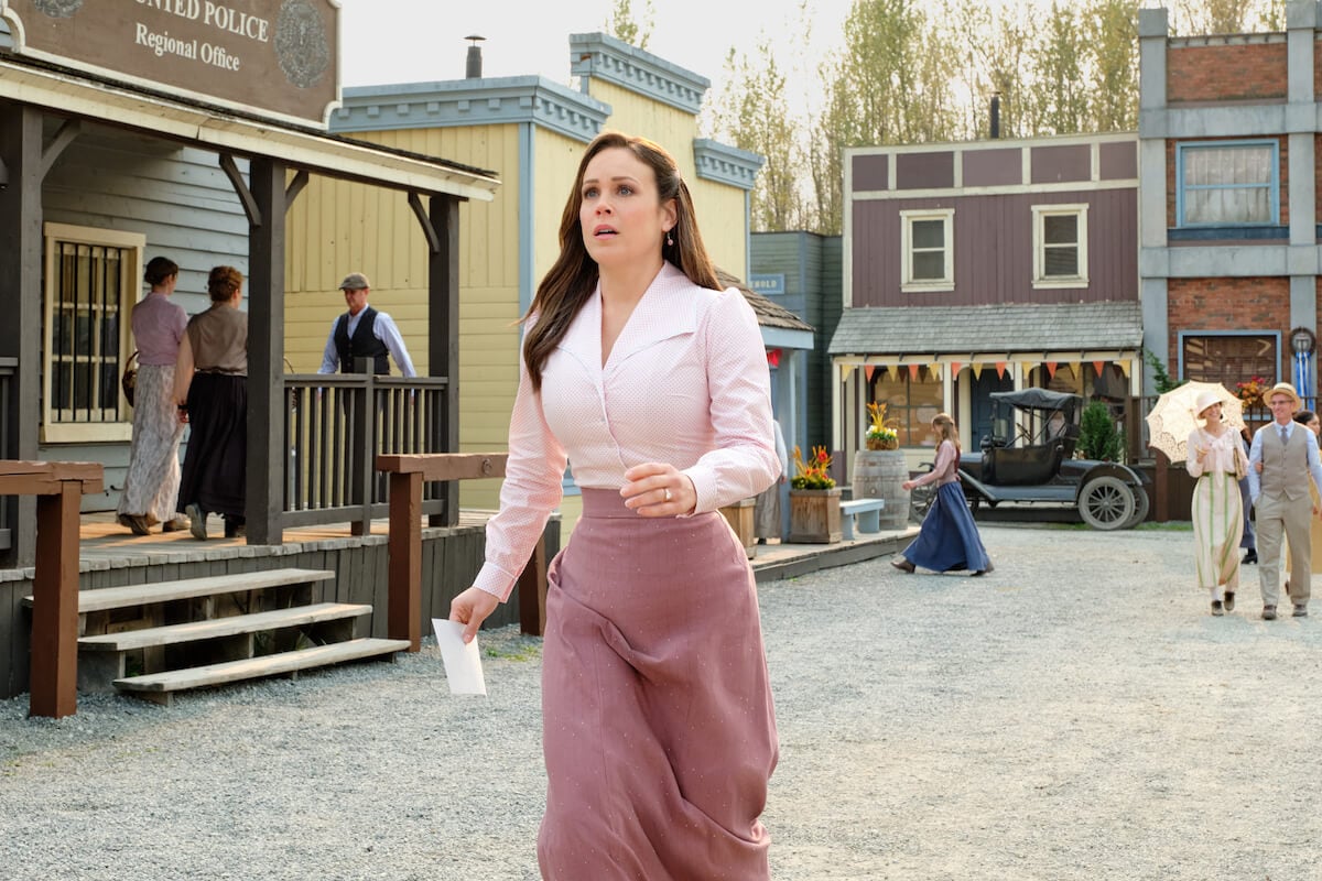 Elizabeth, dressed in pink and looking worried, running down the street in 'When Calls the Heart' Season 10