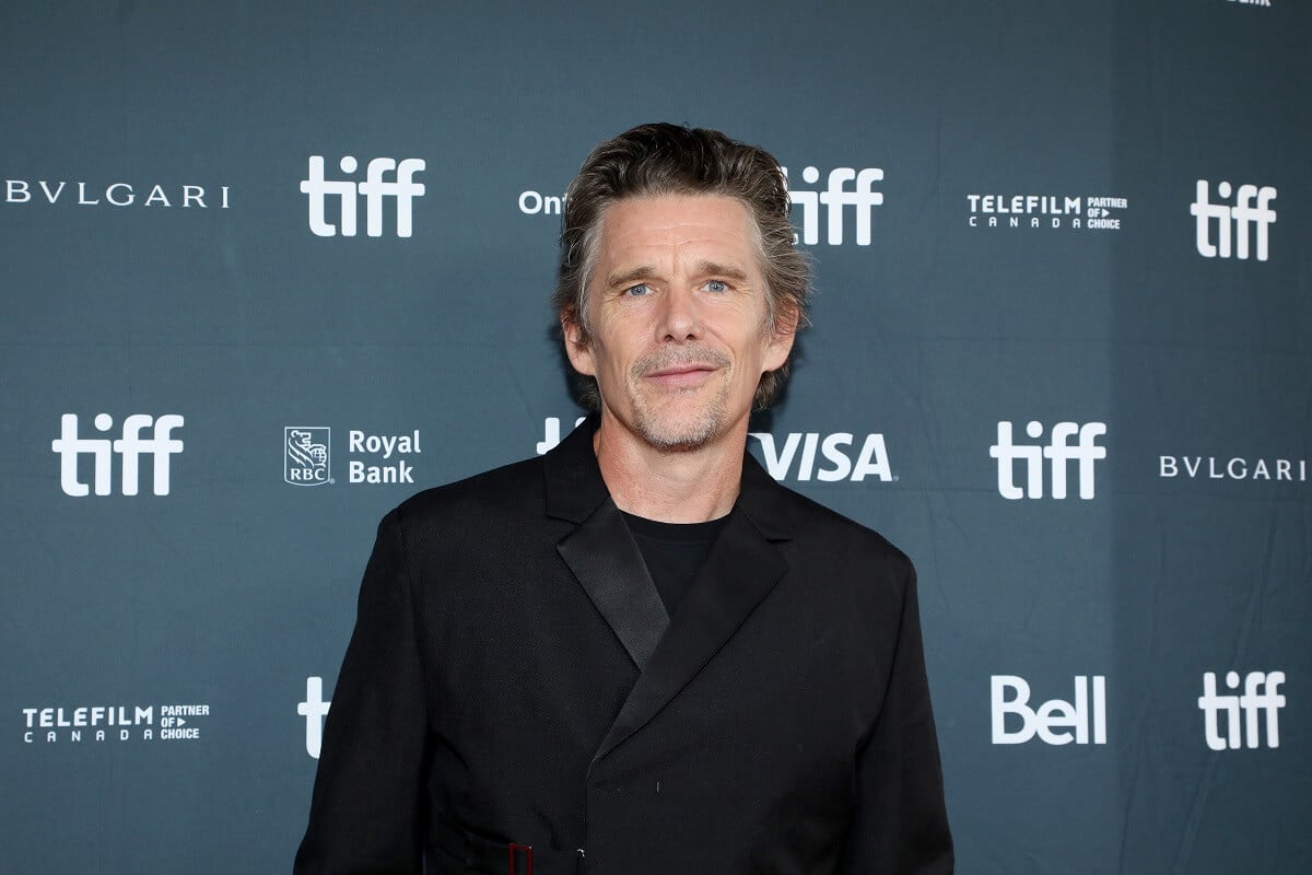 Ethan Hawke taking a picture posing at the premiere of 'Wildcat' in a black suit.