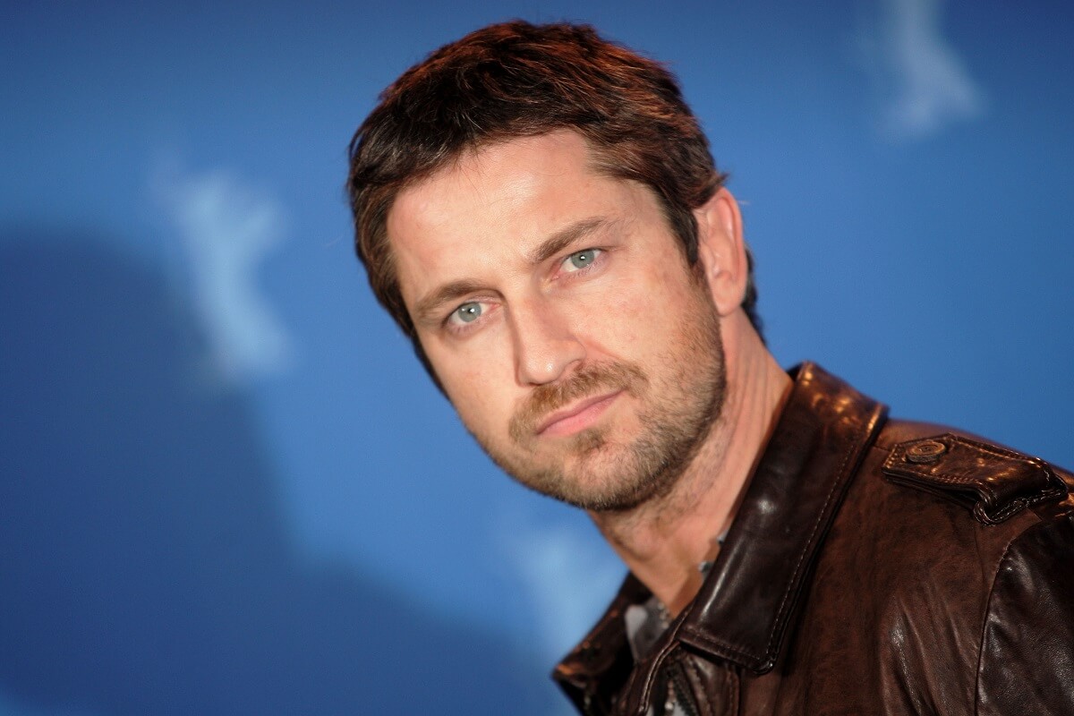 Gerard Butler posing in a black jacket while attending a photocall for the film '300'.
