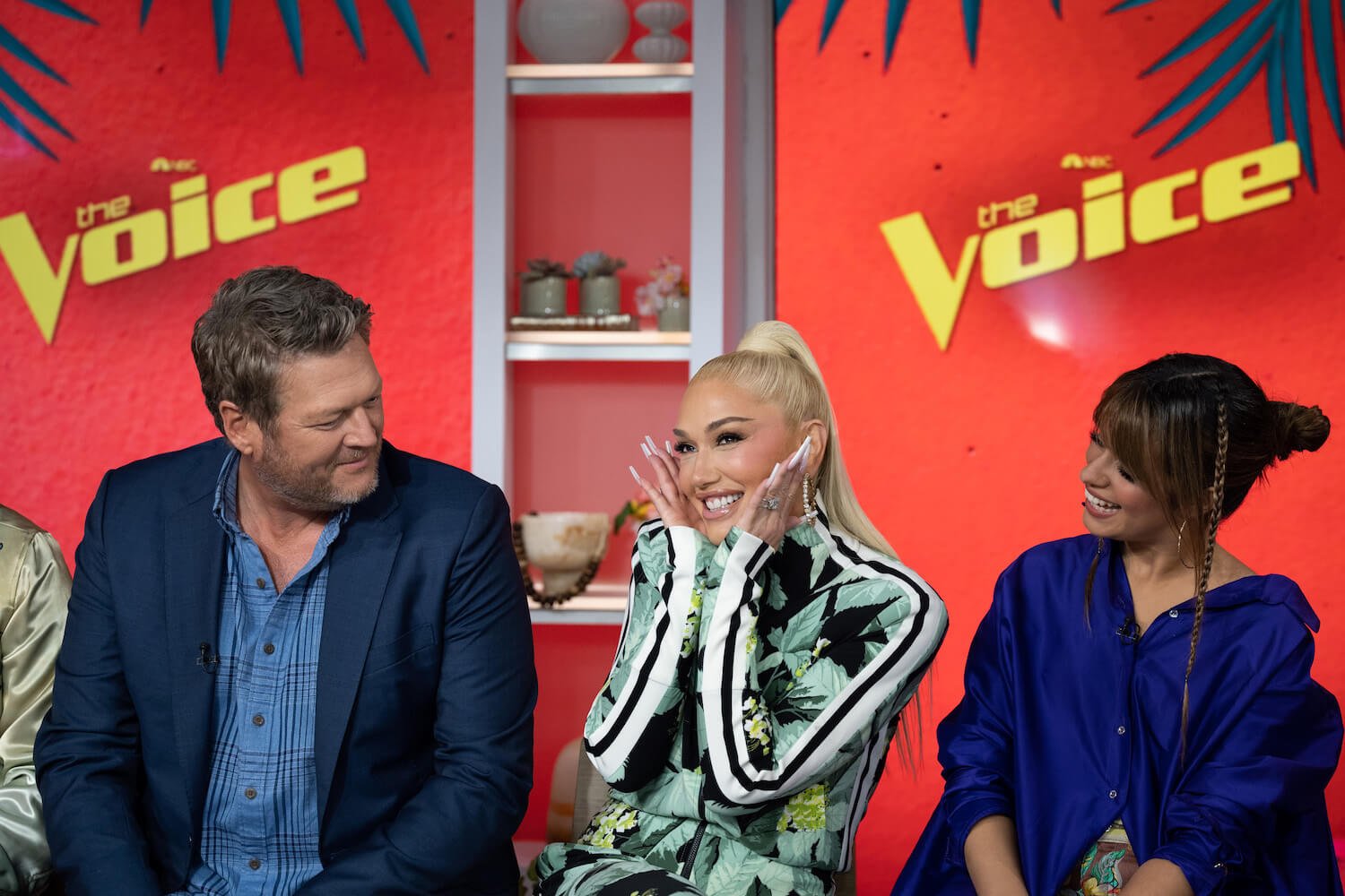 Gwen Stefani in front of 'The Voice' background with Blake Shelton on her right and Camila Cabello on her left