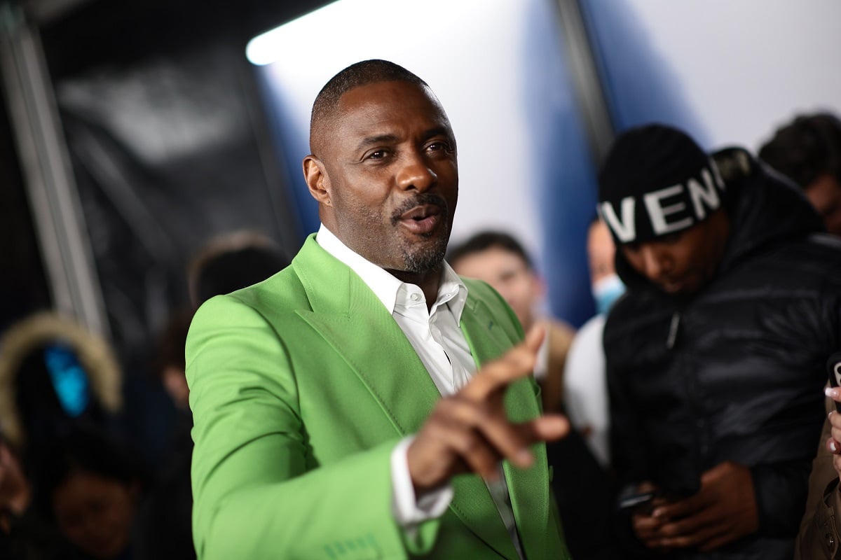Idris Elba talking to someone in a green suit at the 'Luther: The Fallen Sun' premiere'.