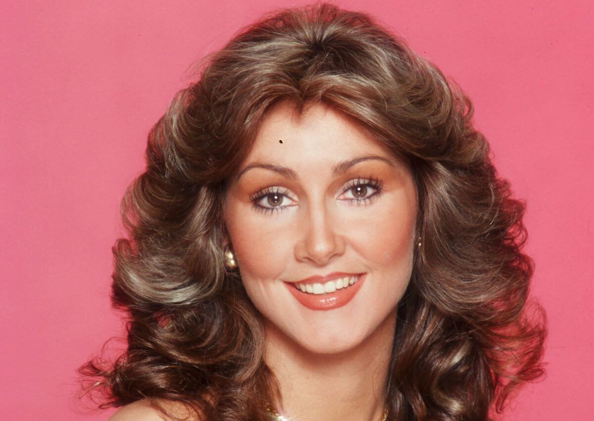 Linda Thompson smiles against a pink background.
