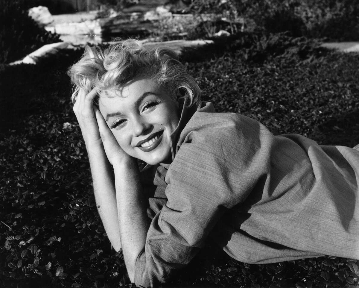 Marilyn Monroe is seen sitting in the grass in an undated photo