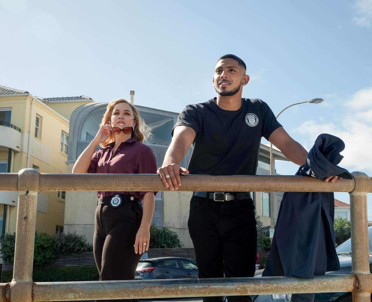 Man leaning on a railing with a woman behind him in 'NCIS: Sydney'