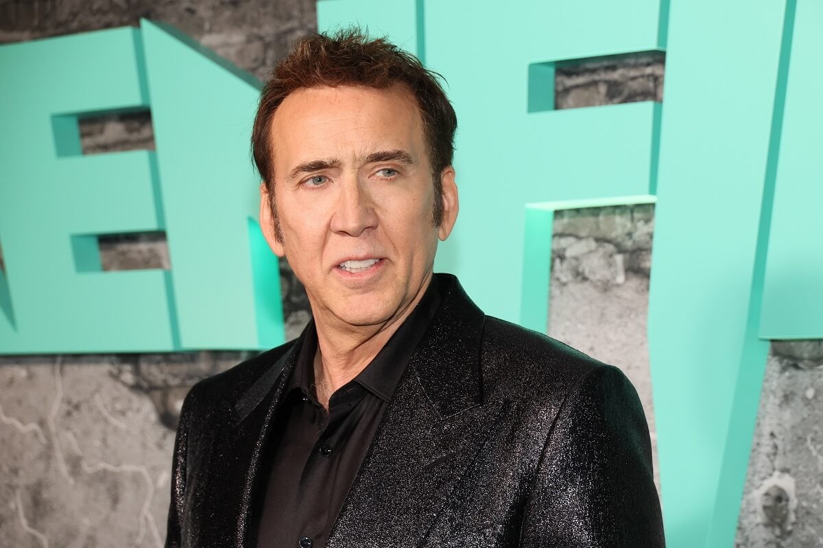 Nicolas Cage taking a picture at the premiere of the film 'Reinfeld' in a black suit.