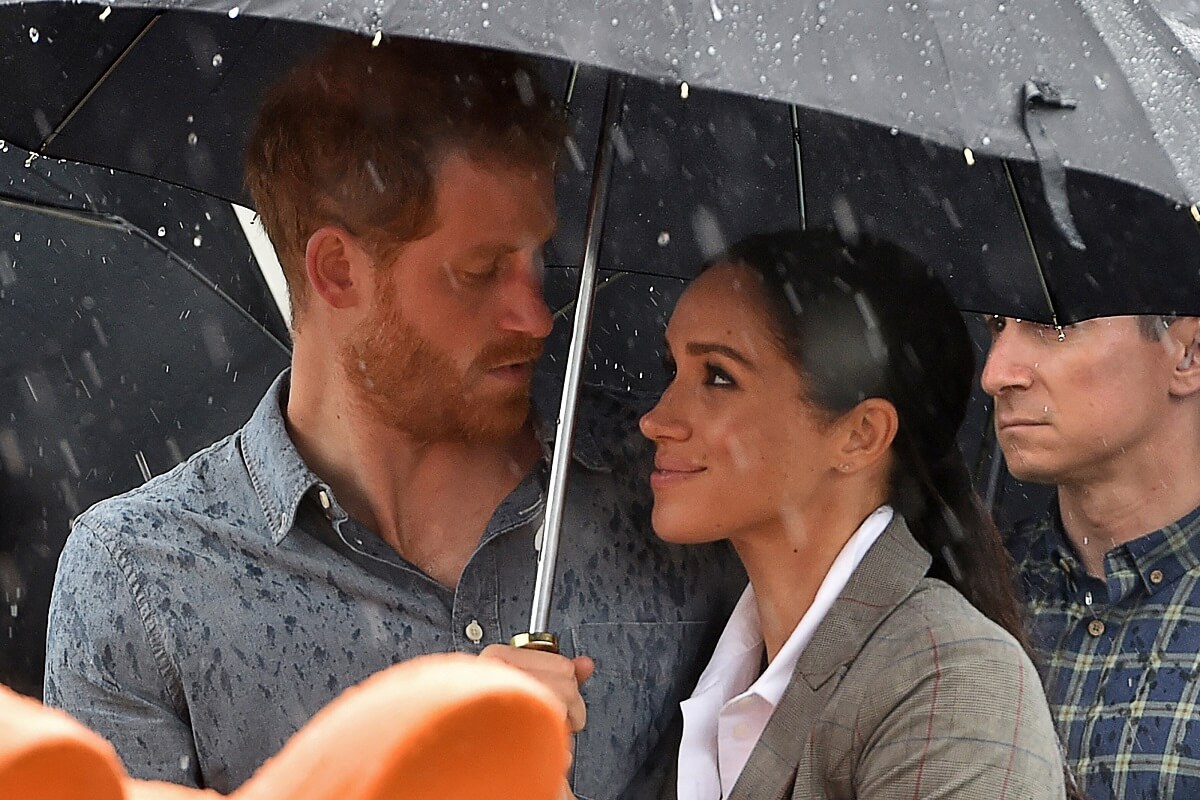 Prince Harry and Meghan Markle watch aboriginal dances under an umbrella at Victoria Park in Dubbo