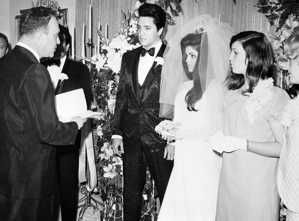 Nevada Supreme Court Justice David Zenoff holds a book and stands in front of Elvis Presley, Priscilla Presley, and Priscilla's sister Michelle Beaulieu on their wedding day.