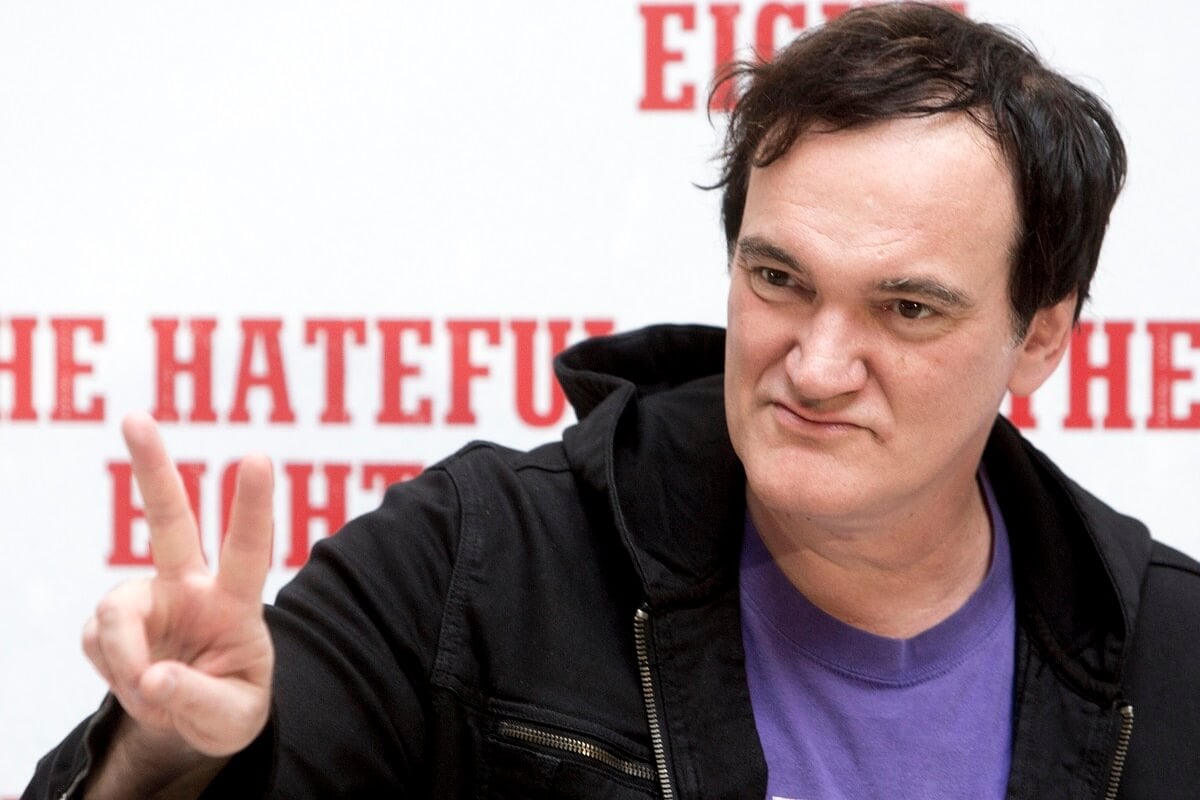 Quentin Tarantino posing at a press conference of his movie 'The Hateful Eight' while wearing a jacket and shirt.
