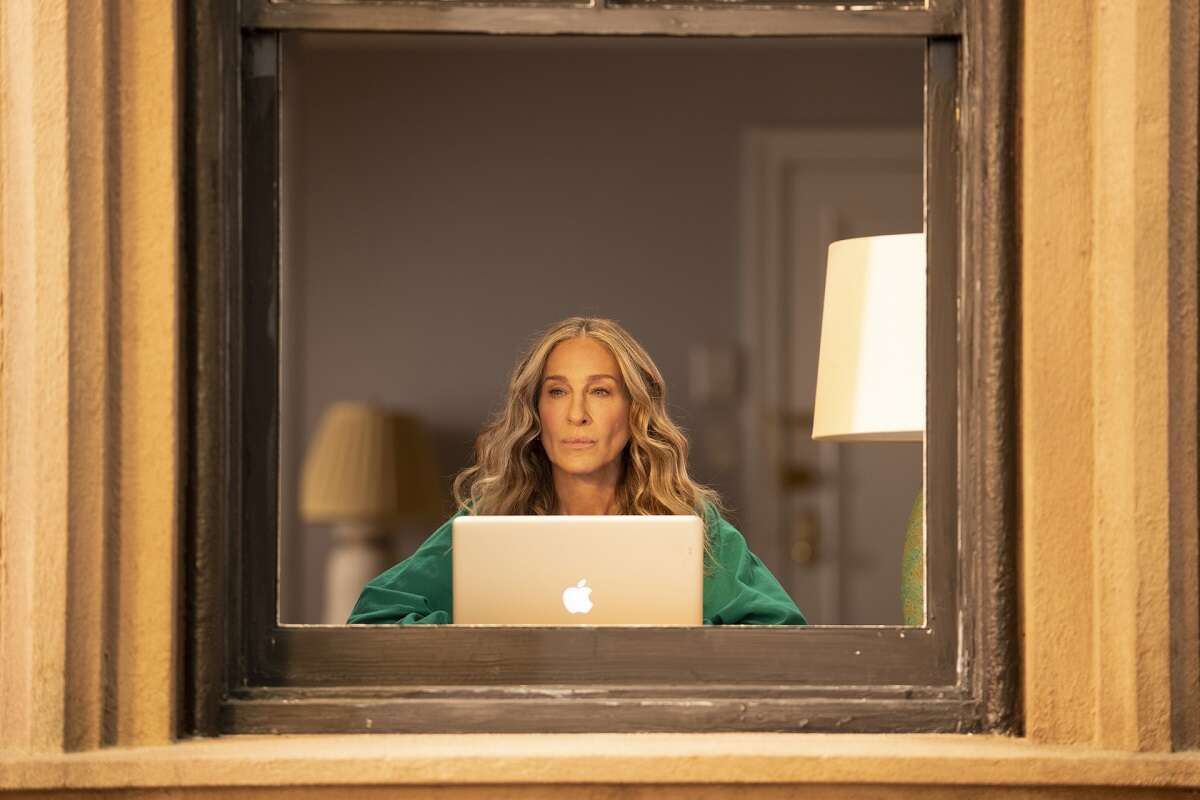 Carrie Bradshaw sits at her computer desk in an episode of 'And Just Like That...'; season 3 of the reboot is upcoming