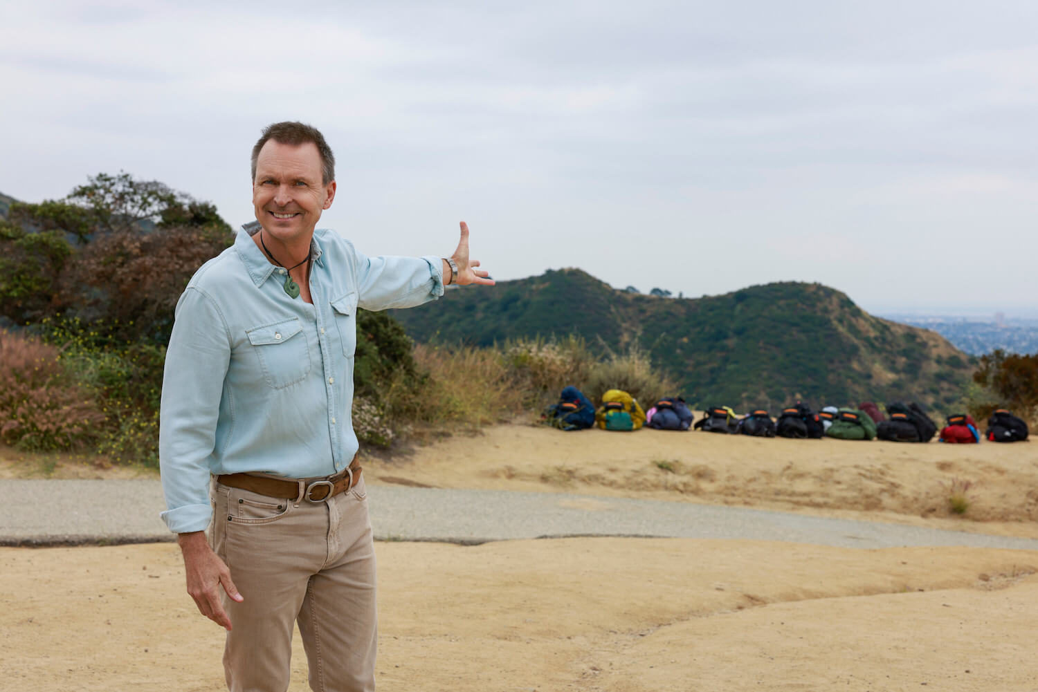 'The Amazing Race' Season 35 host Phil Keoghan smiling and showing the landscape