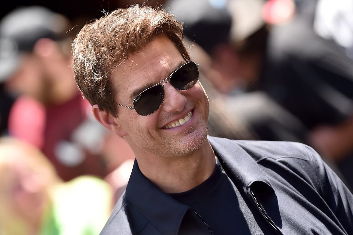 Tom Cruise smiling at 'The Mummy Day' celebration while wearing sunglasses.