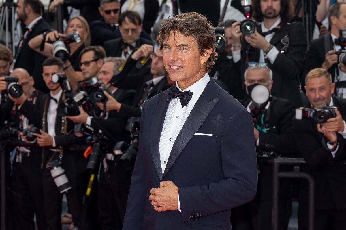 Tom Cruise attending a screening of 'Top Gun Maverick' while posing in a suit.