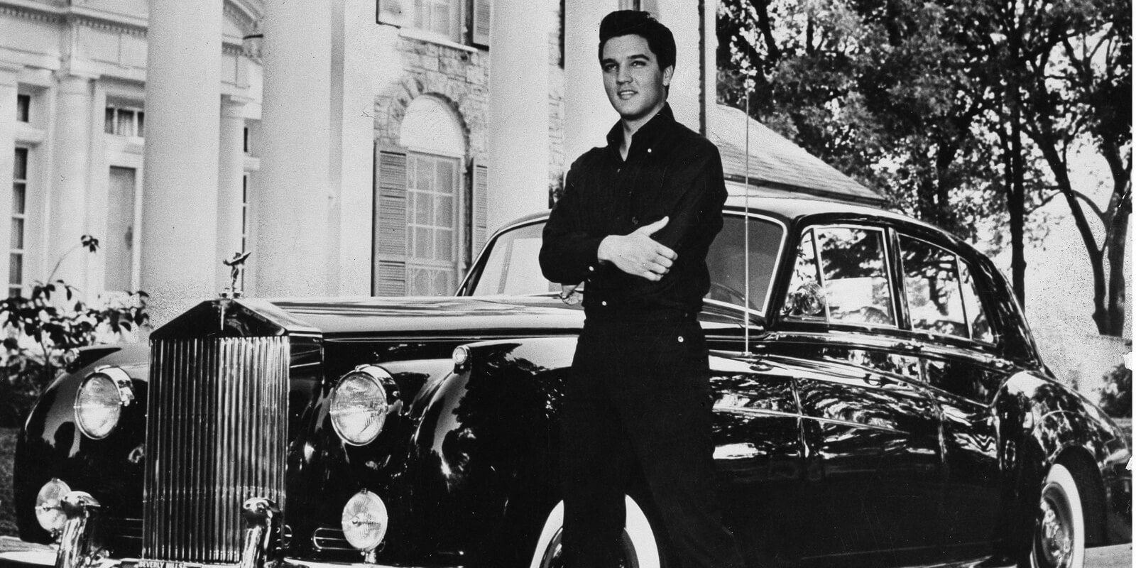 Elvis Presley photographed with one of his cars in front of his Graceland home in Memphis, TN.