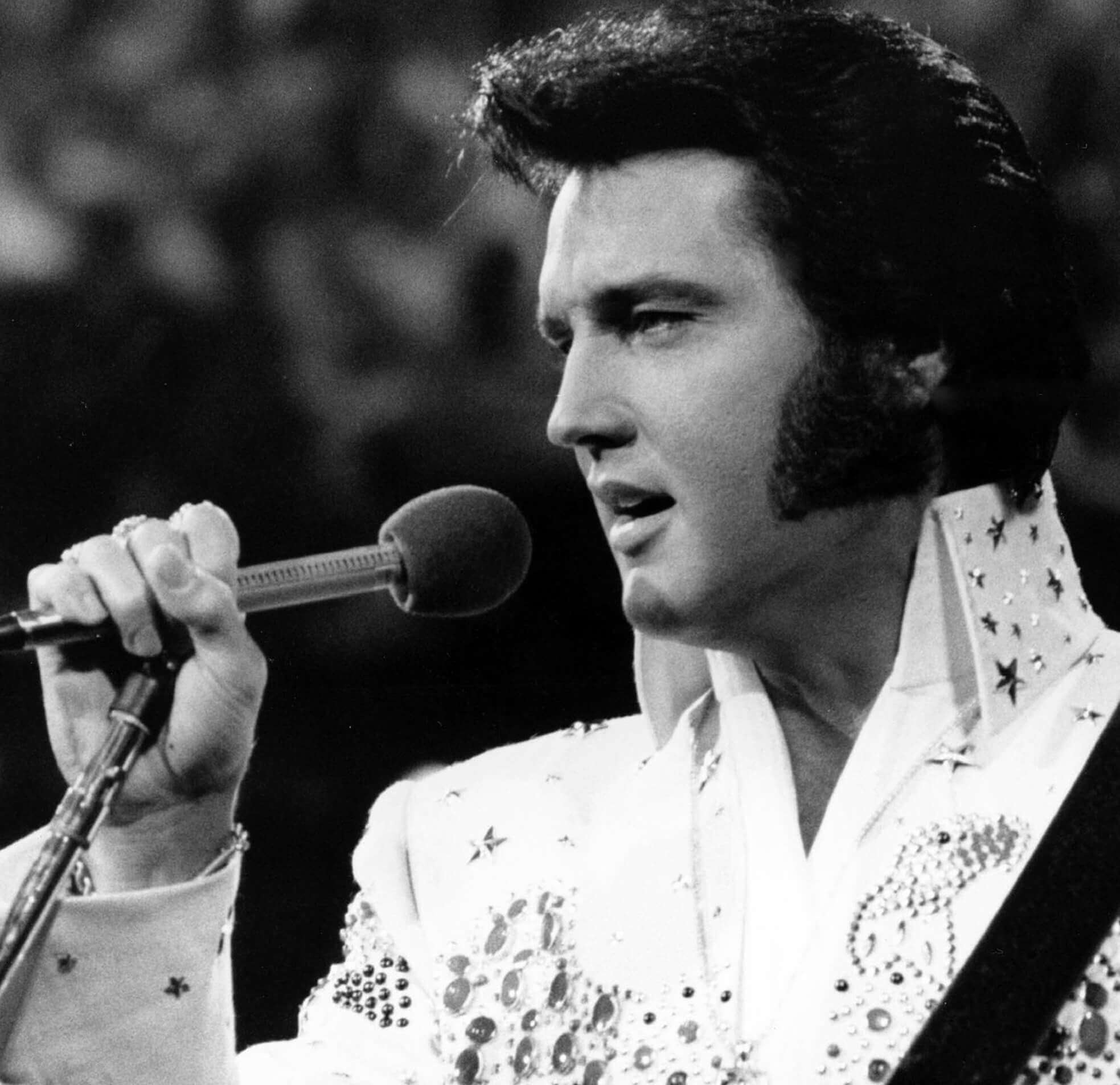 "Suspicious Minds" singer Elvis Presley holding a microphone
