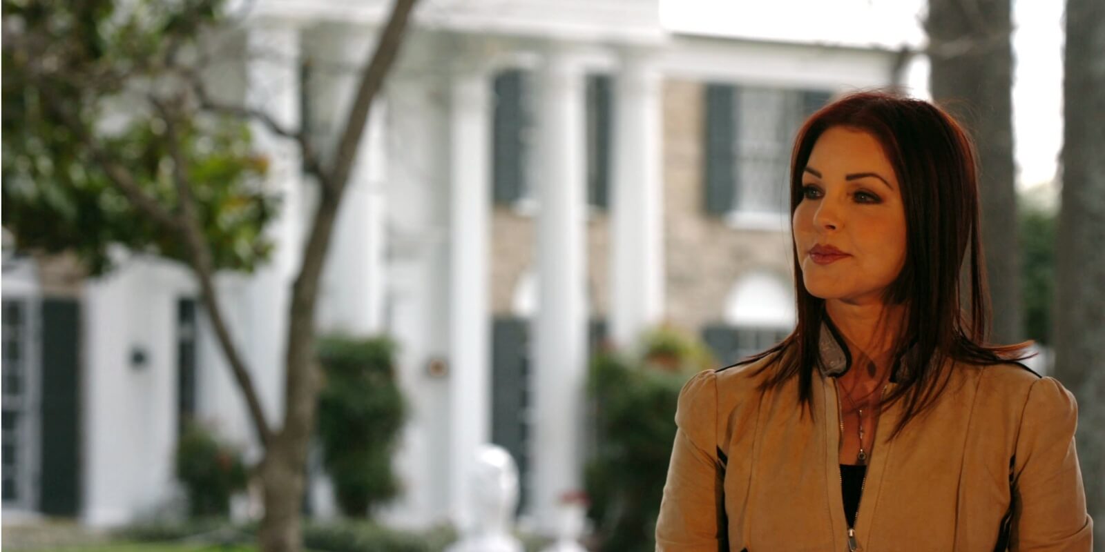 Priscilla Presley poses in front of Elvis Presley's home, Graceland.