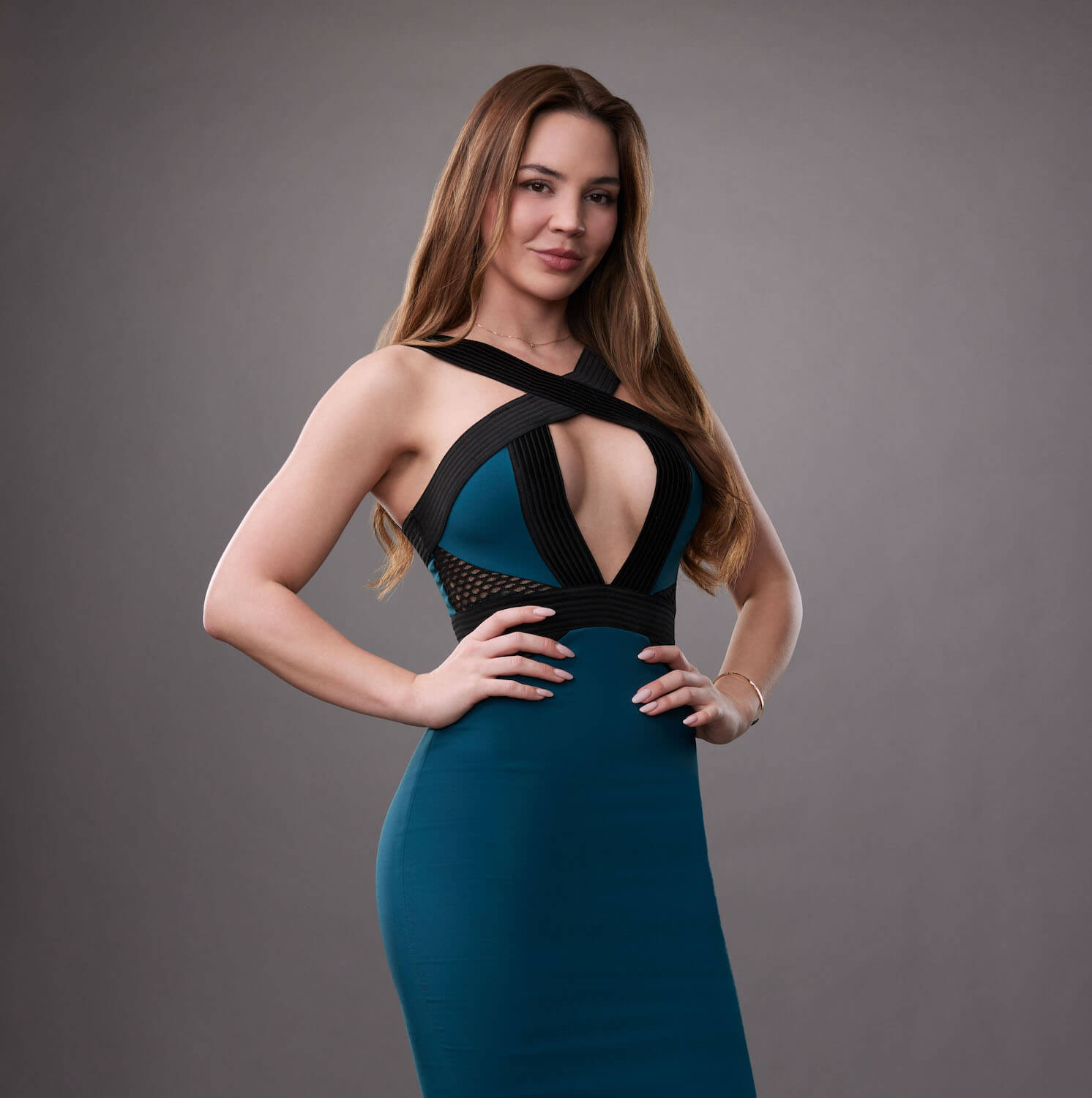 Anfisa Arkhipchenko from 'House of Villains' wearing a blue dress posing with her hands on her hips