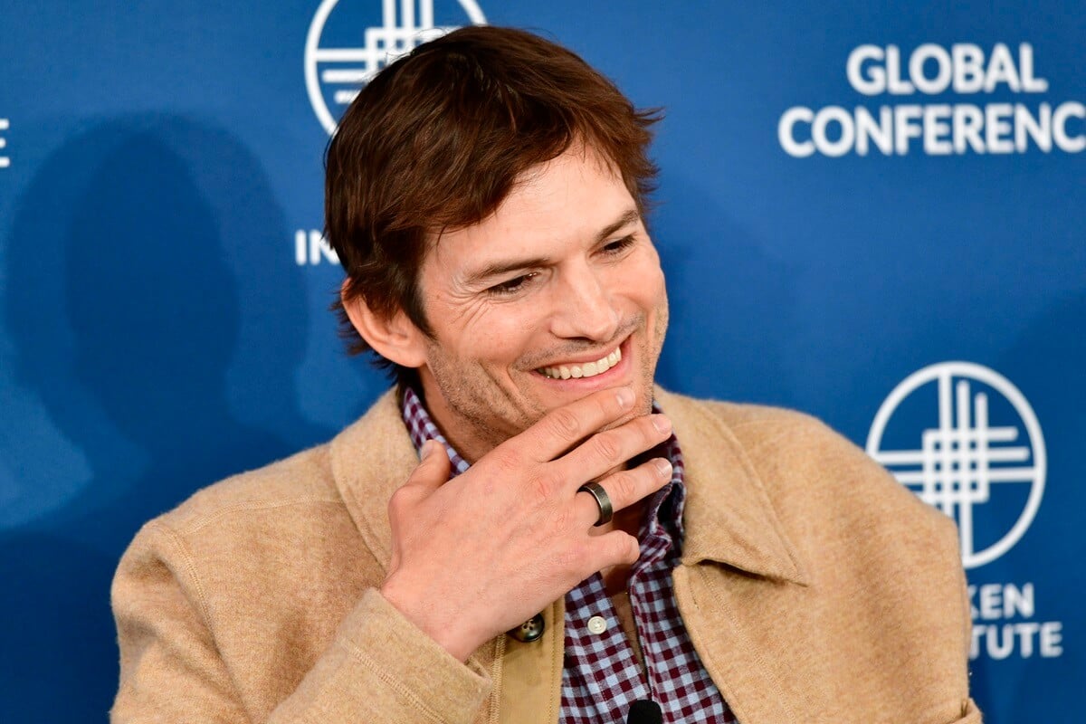 Ashton Kutcher sitting down smiling at the 2023 Milken Institute Global Conference