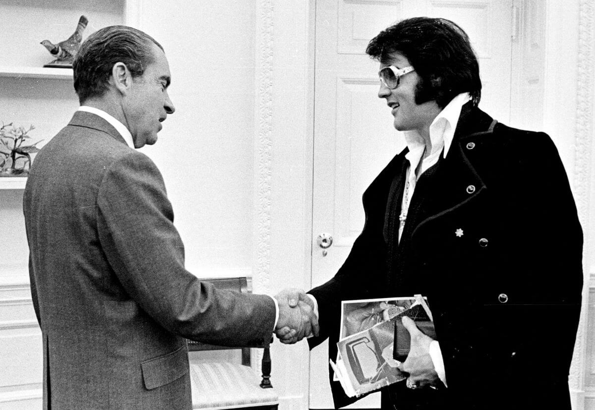 A black and white picture of Richard Nixon shaking hands with Elvis Presley.