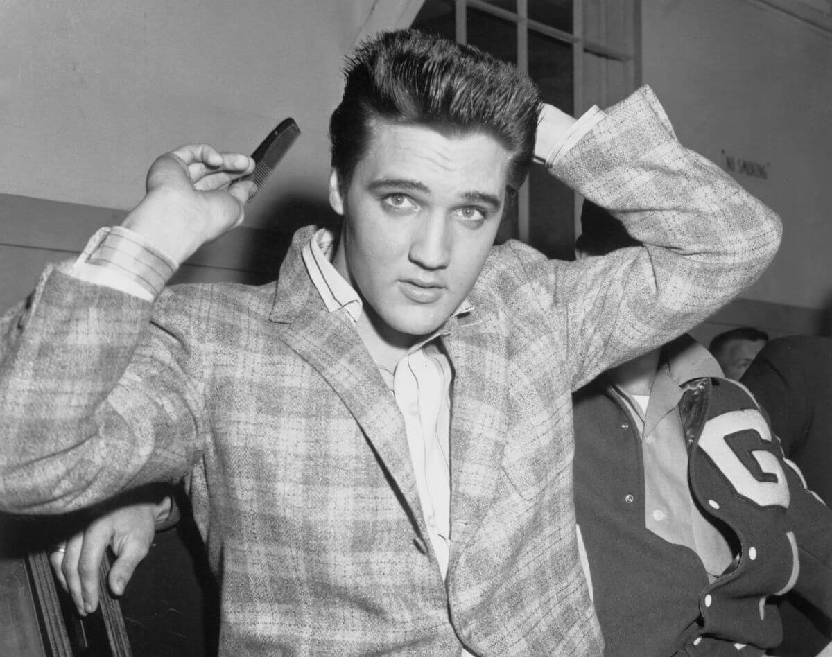 A black and white picture of Elvis Presley combing his hair.