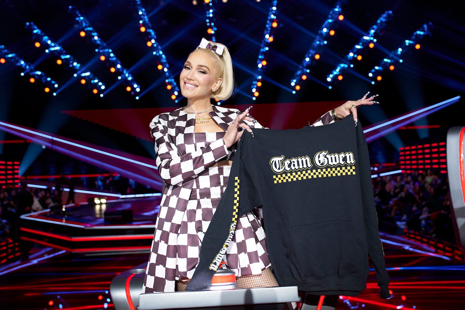 'The Voice' Season 24 coach Gwen Stefani holding up a 'Team Gwen' shirt and smiling