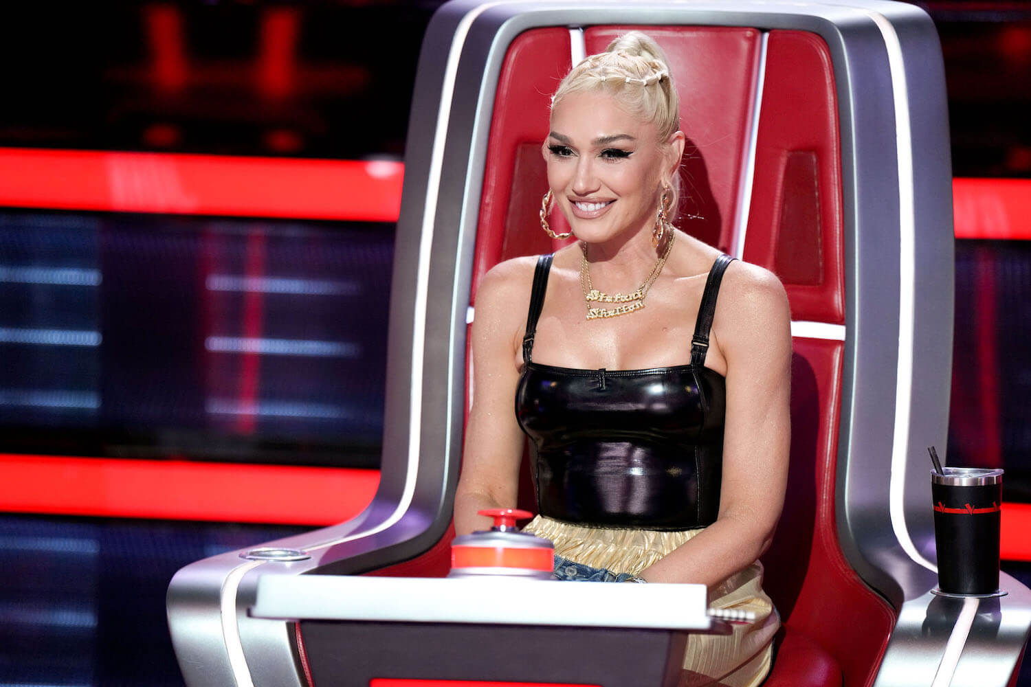 Gwen Stefani from 'The Voice' Season 24 sitting in a coach chair