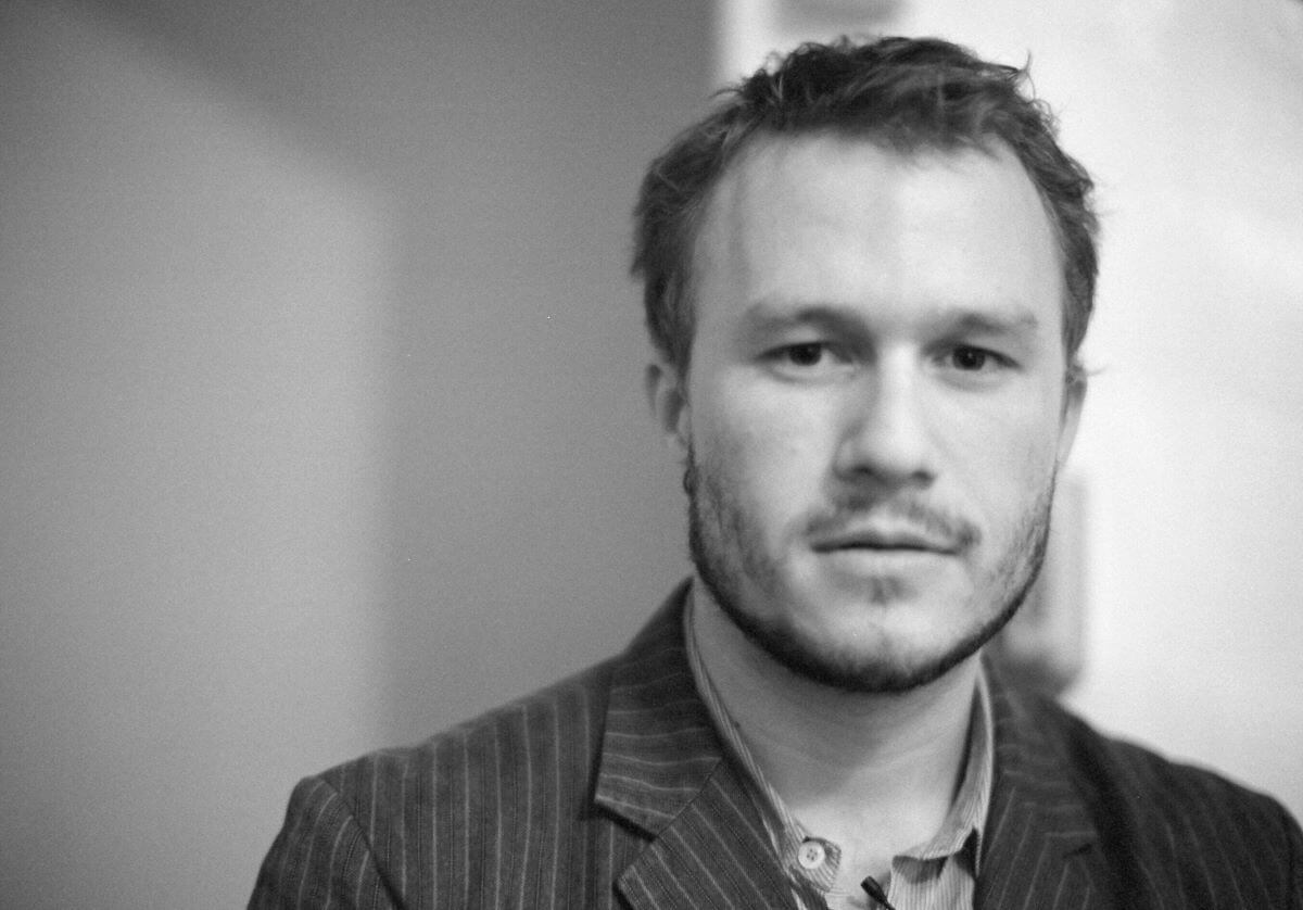 A black and white picture of Heath Ledger wearing a jacket and looking into the camera.