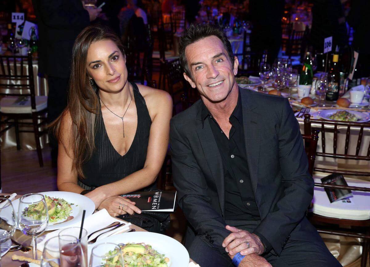 Jeff Probst and his wife Lisa Ann Russell sit at a table together in front of salads.