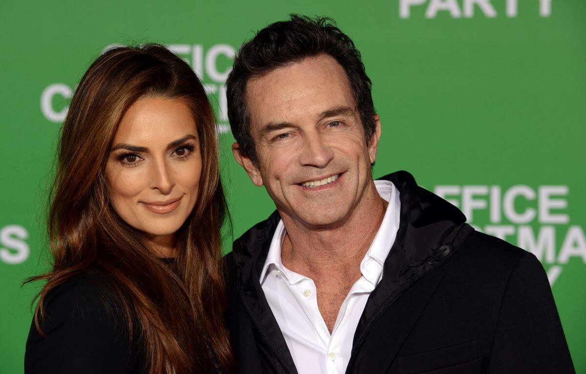 Lisa Ann Russell and Jeff Probst pose together in front of a green background.