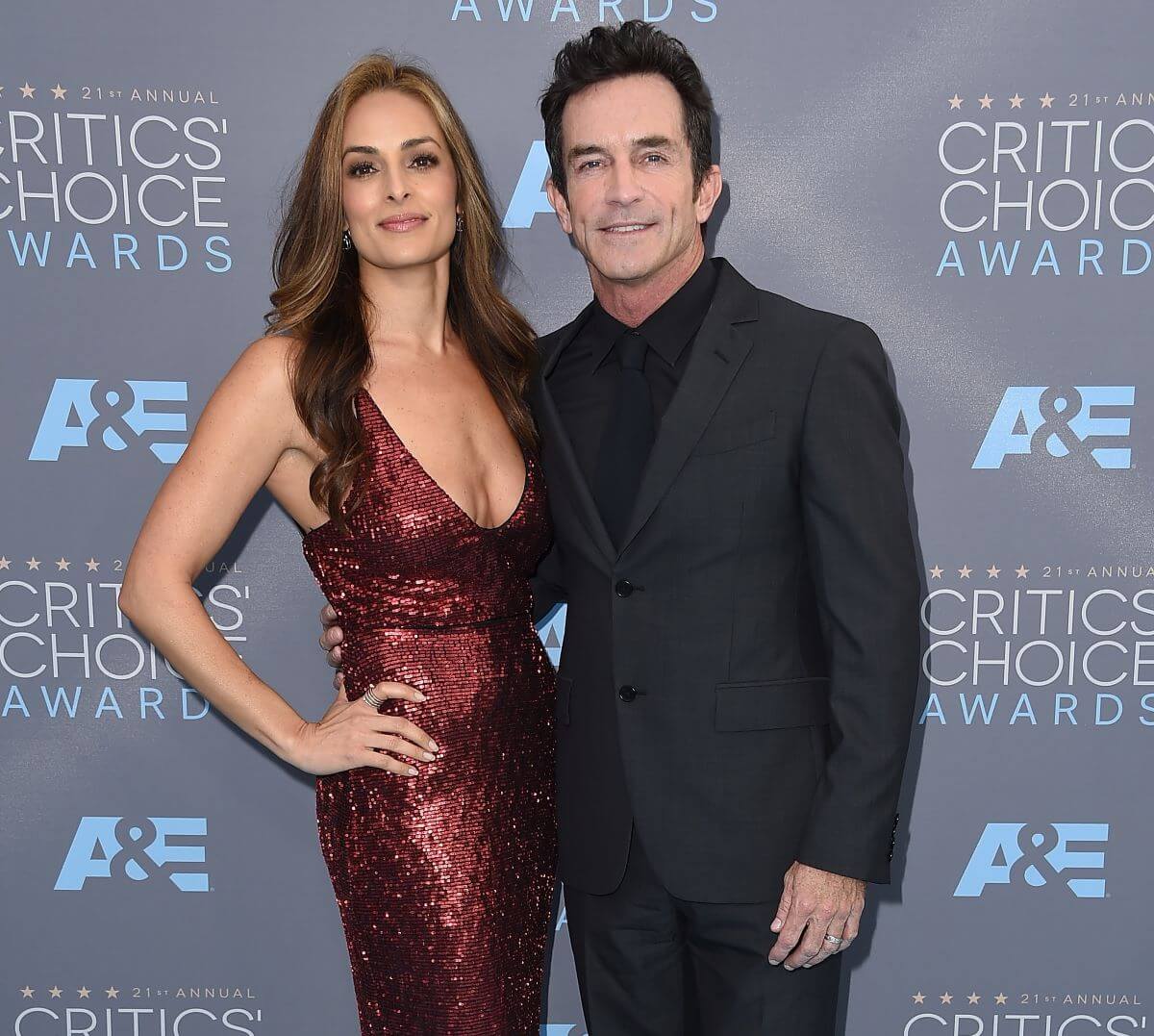 Lisa Ann Russell wears a red dress and stands with Jeff Probst, who wears a black suit.