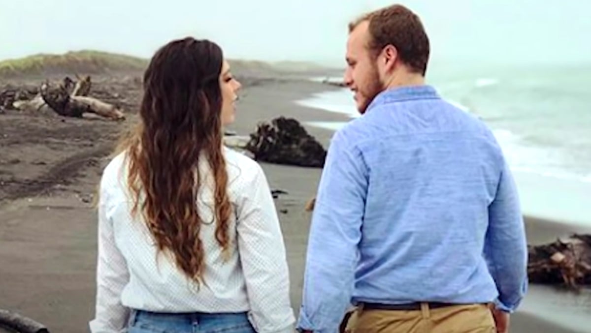 Josiah Duggar and Lauren Swanson walk along a beach during their engagement