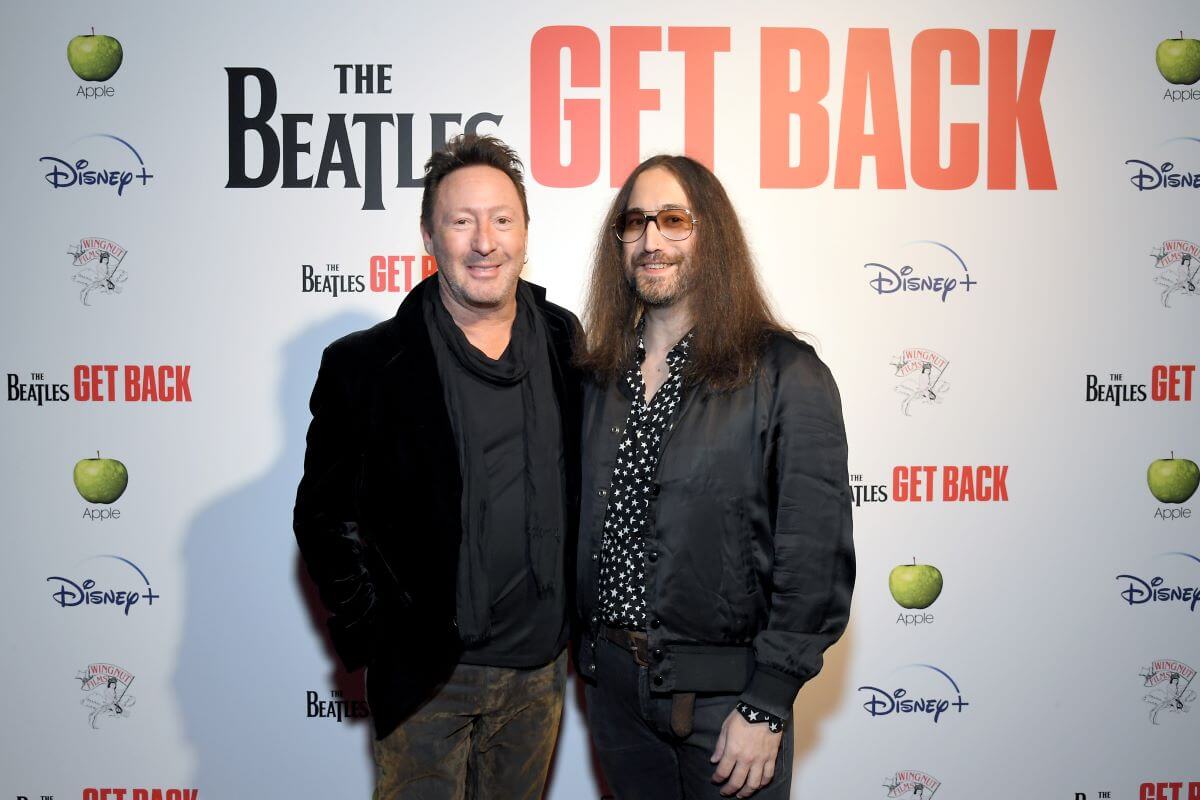 Julian and Sean Lennon wear black and pose together in front of a step and repeat for 'The Beatles Get Back.'