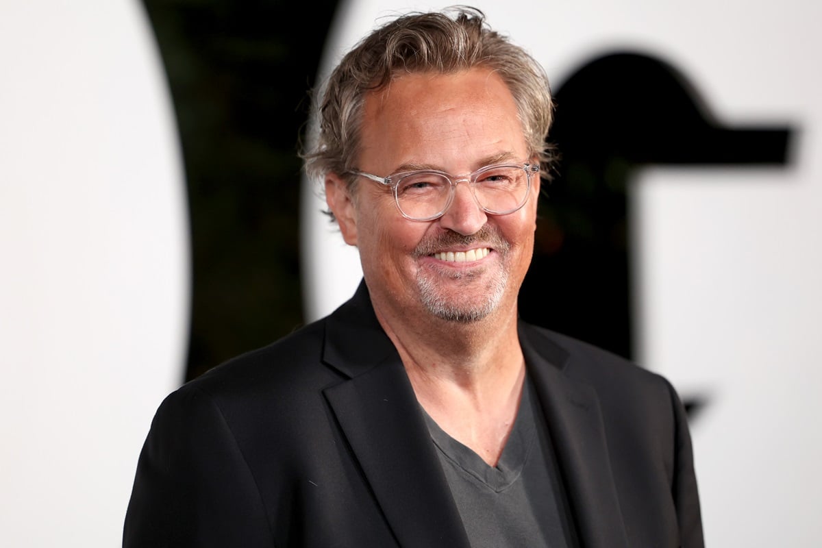 Matthew Perry posing at the GQ Men of the Year Party, wearing a black suit smiling.