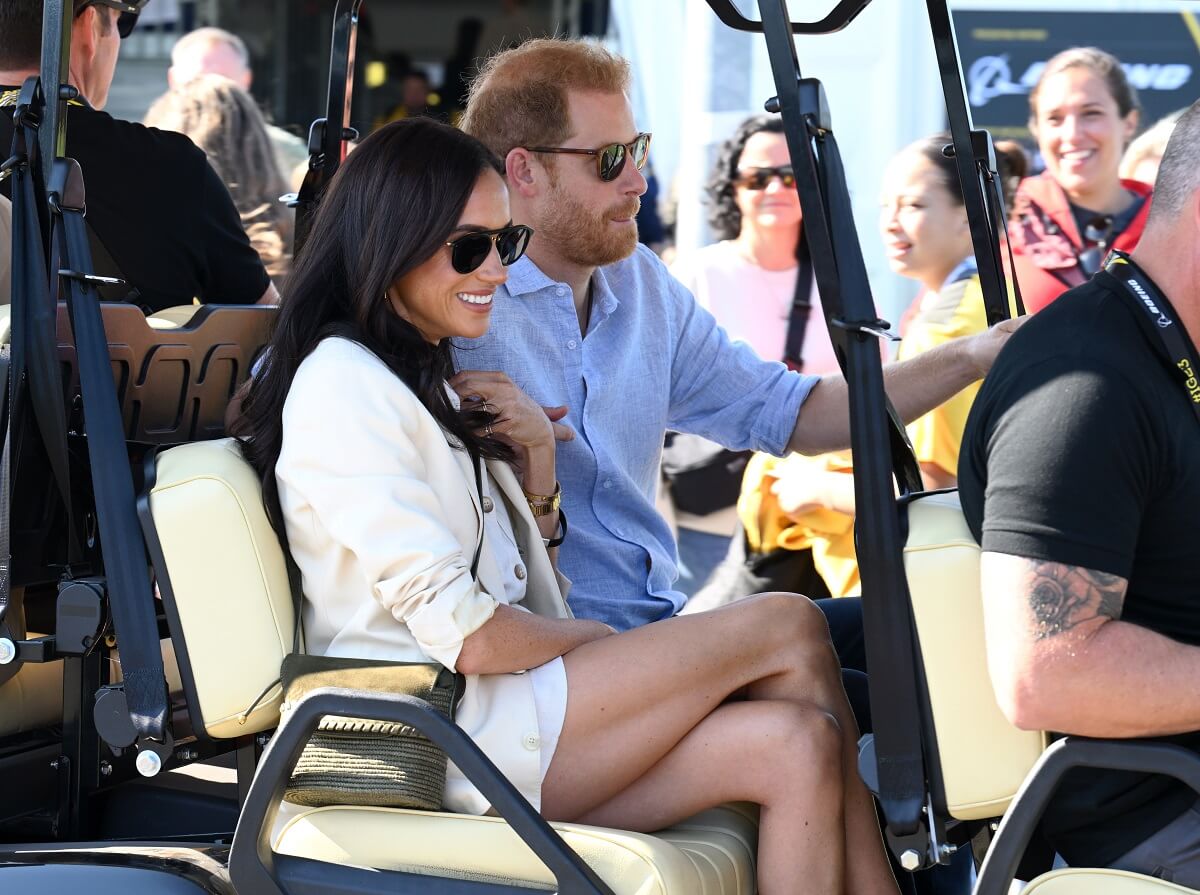 Meghan Markle smiling as she rides in cart with Prince Harry to attend the cycling medal ceremony at the Cycling Track during the Invictus Games Düsseldorf 2023