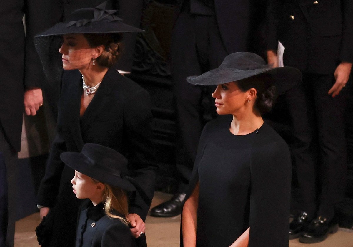 Meghan Markle, who is seen in viral video touching Kate Middleton during an awkward moment, at Queen Elizabeth II's funeral with Princess Charlotte