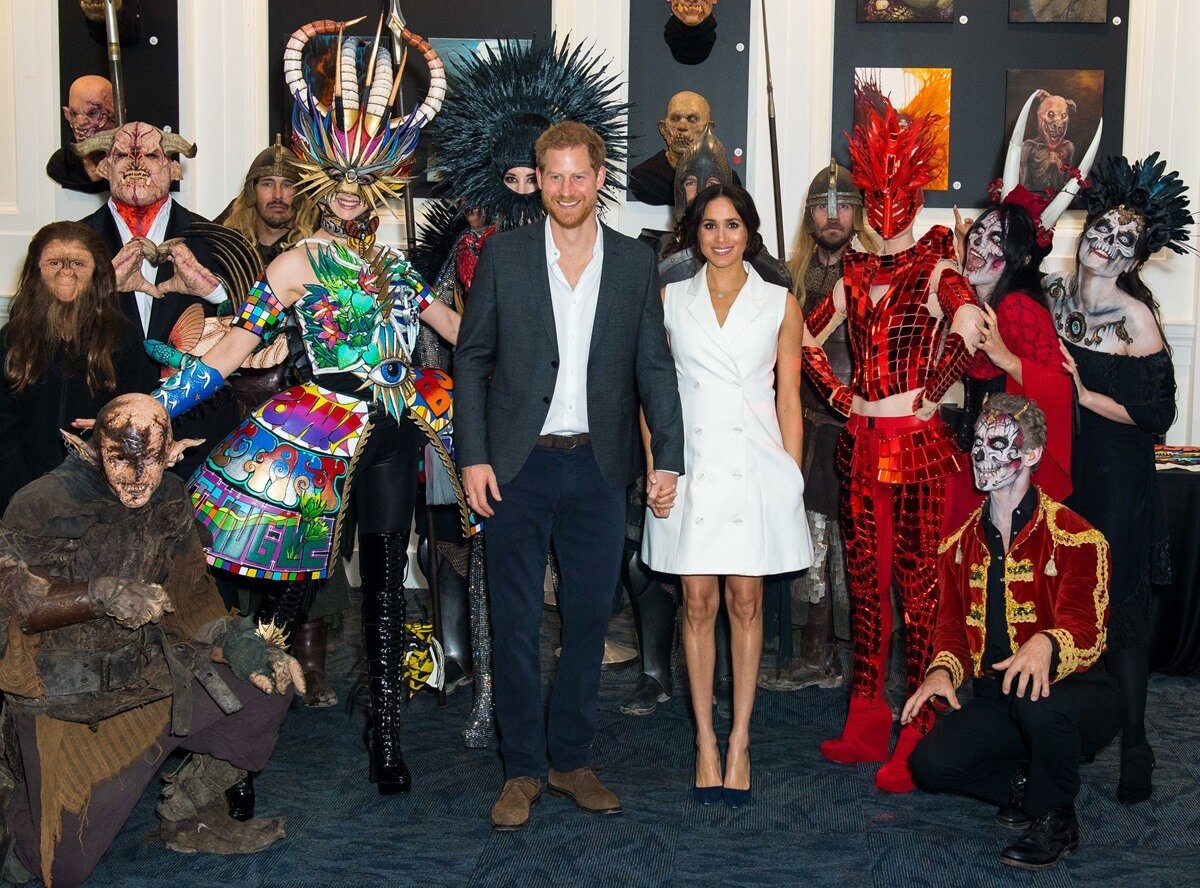 Prince Harry and Meghan Markle pose for a photo with models wearing the work of industry leading artists in film, sculpture and costume design in New Zealand