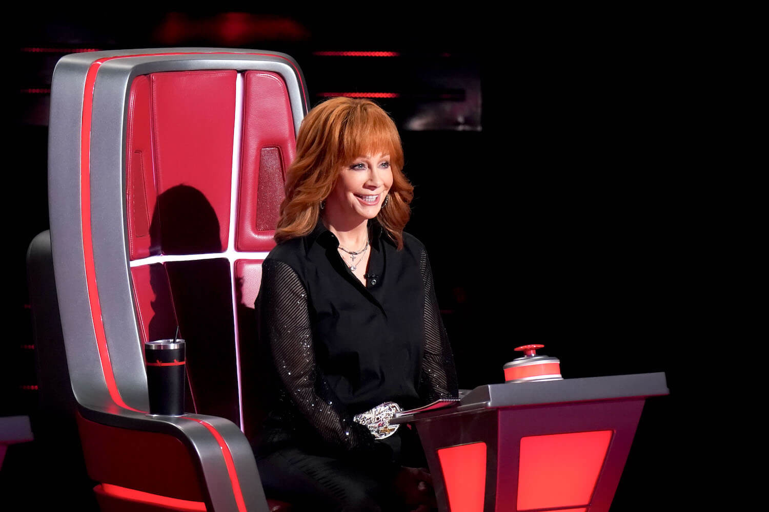 Reba McEntire sitting in a red coach chair during 'The Voice' Season 24 Blind Auditions