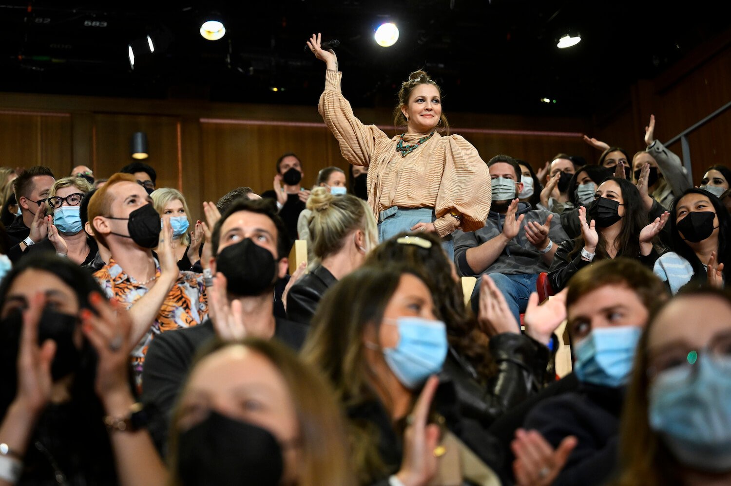 'The Drew Barrymore Show' star Drew Barrymore in a crowd of masked people with her hand up