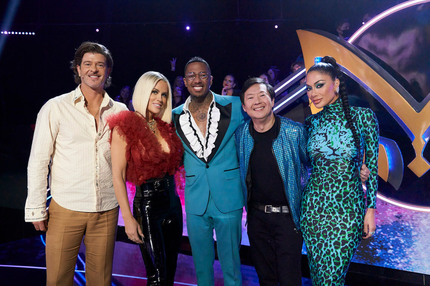 'The Masked Singer' Season 10 judges standing with Nick Cannon and looking at the camera