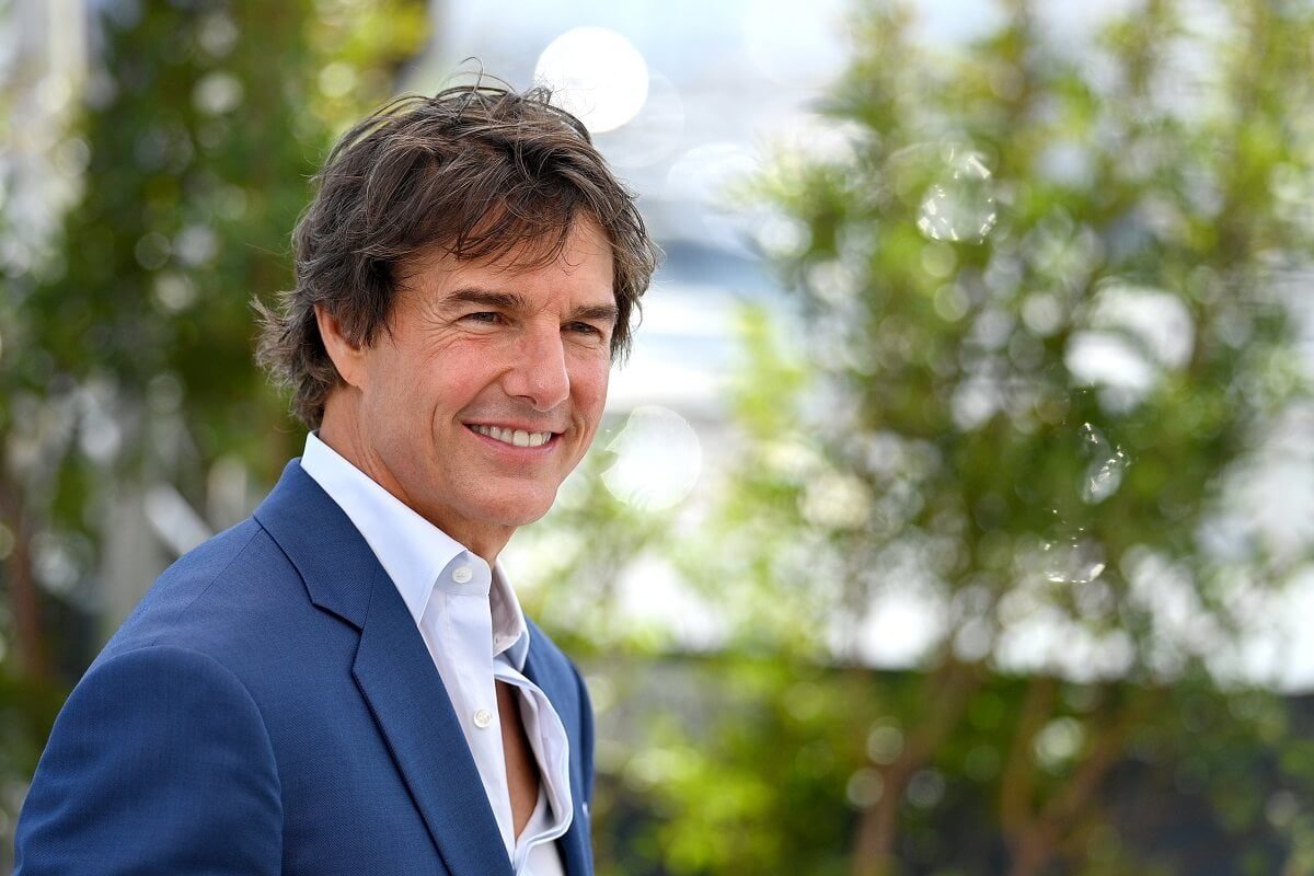 Tom Cruise posing in a blue suit at a photocall for 'Top Gun: Maverick'.