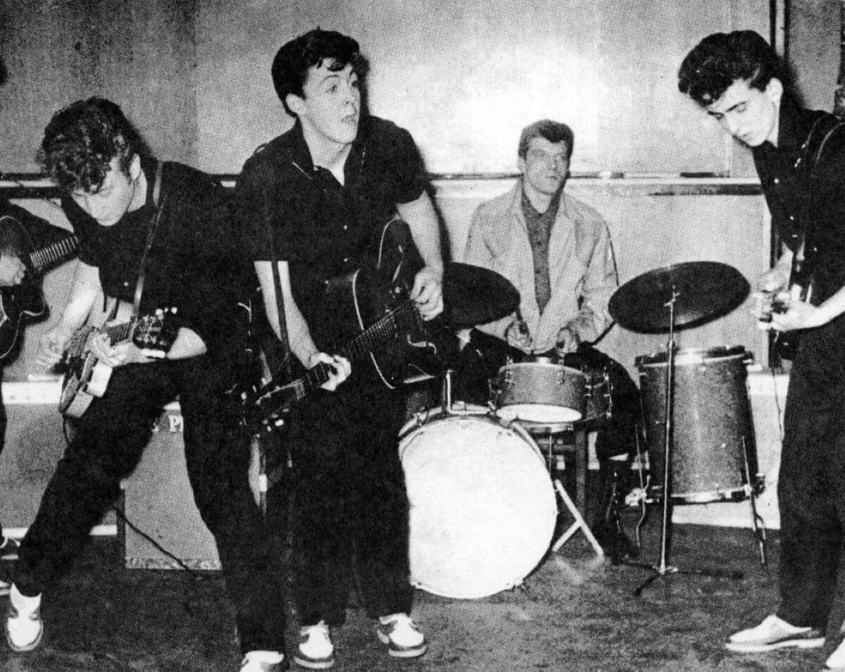 A black and white picture of The Beatles performing.