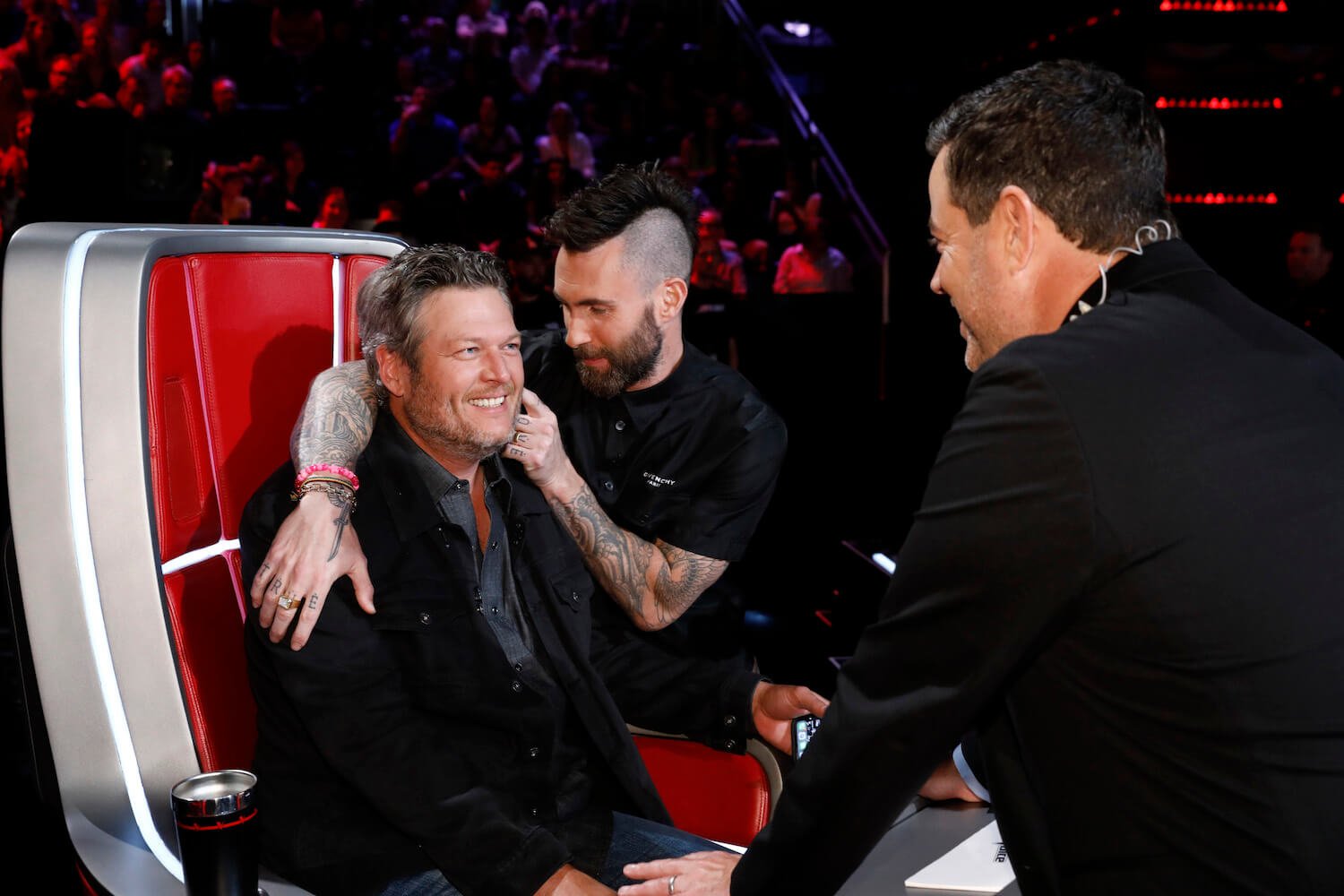 Adam Levine touching Blake Shelton's face in 'The Voice' with host Carson Daly watching