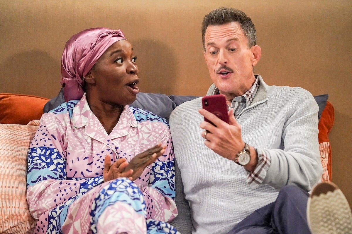 Abishola and Bob looking shocked as they look at a phone in 'Bob Hearts Abishola'